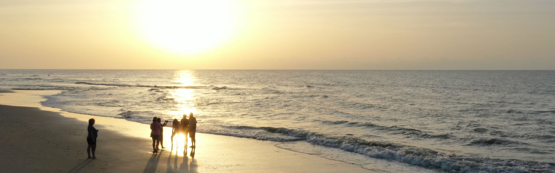 Group of people on beach watching the sunset