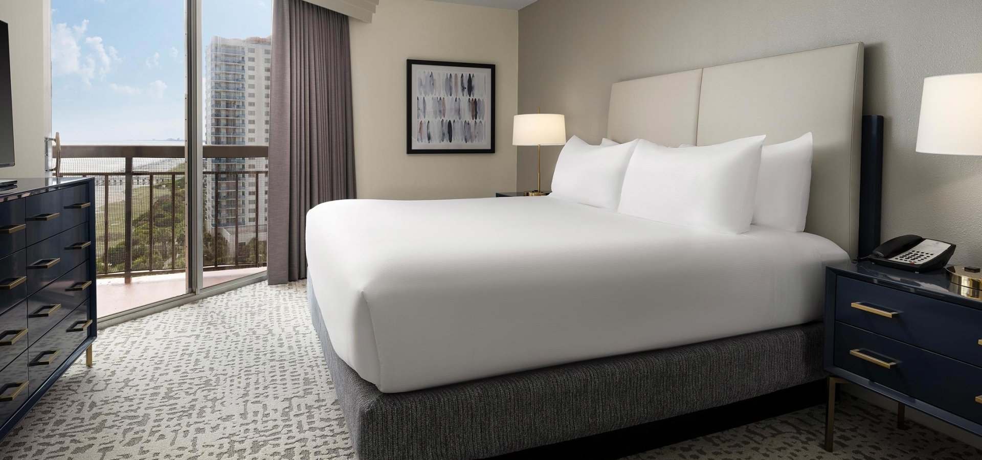 Hotel bed in Embassy Suites bedroom with balcony access