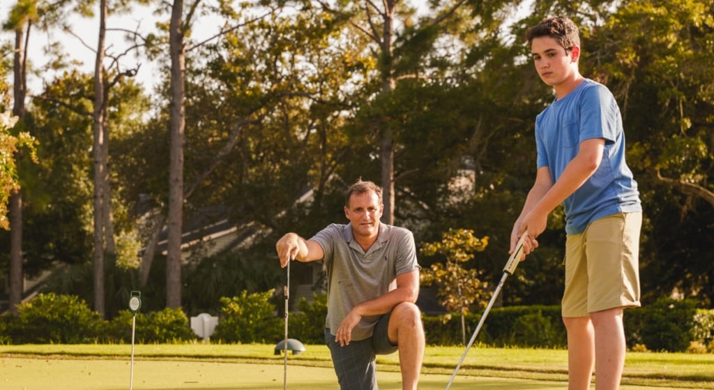 Father watching son putt