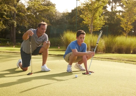 Father and son on putting green at 78Fitness looking at their next shot