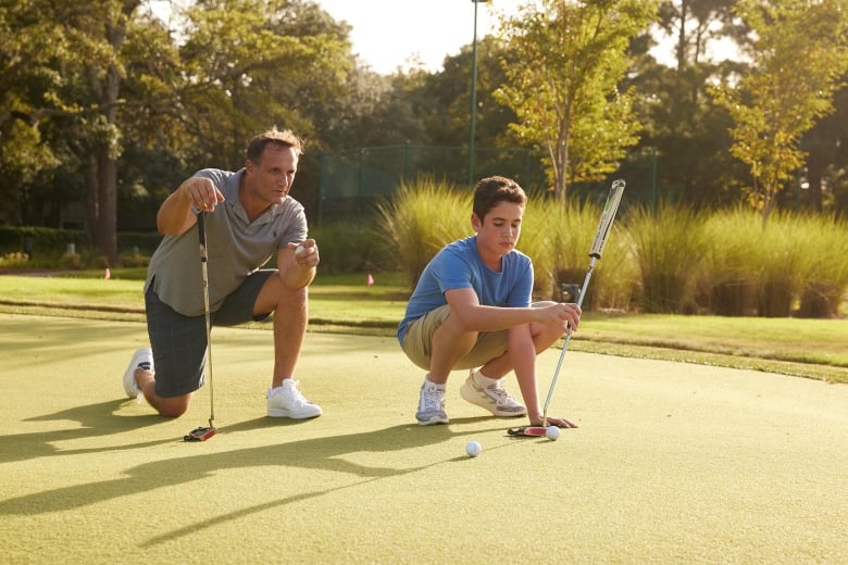 Father and son on putting green at 78Fitness looking at their next shot