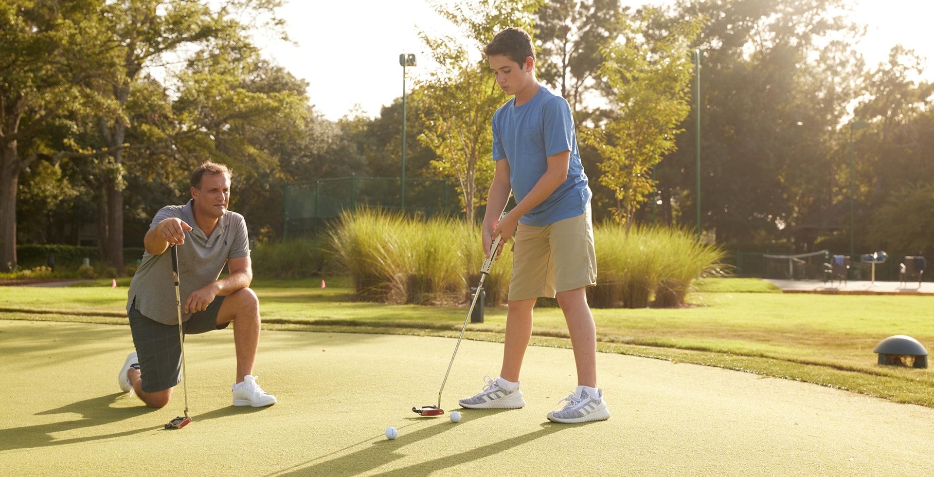 Father and son on putting green and the son is about to take his shot