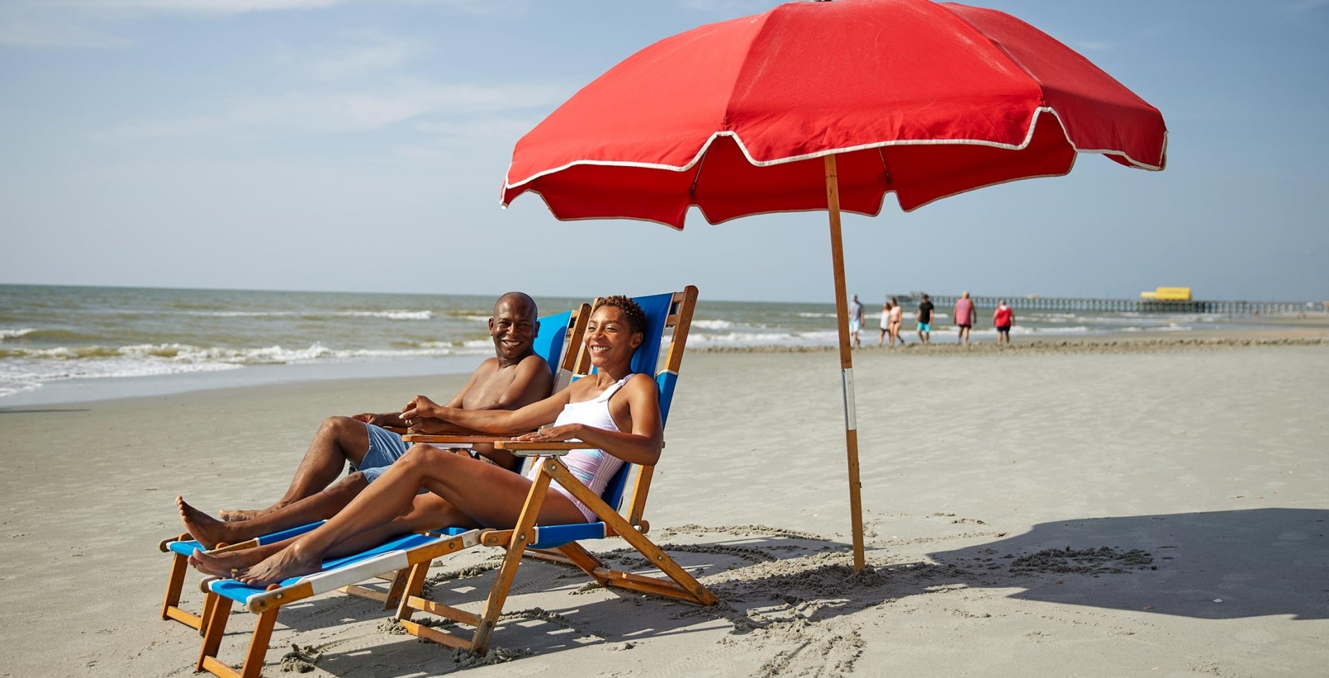Couple laughing with each other underneath an umbrella on the beach