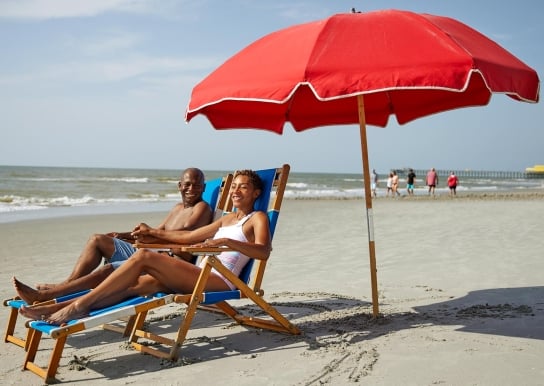 Couple laughing with each other underneath an umbrella on the beach