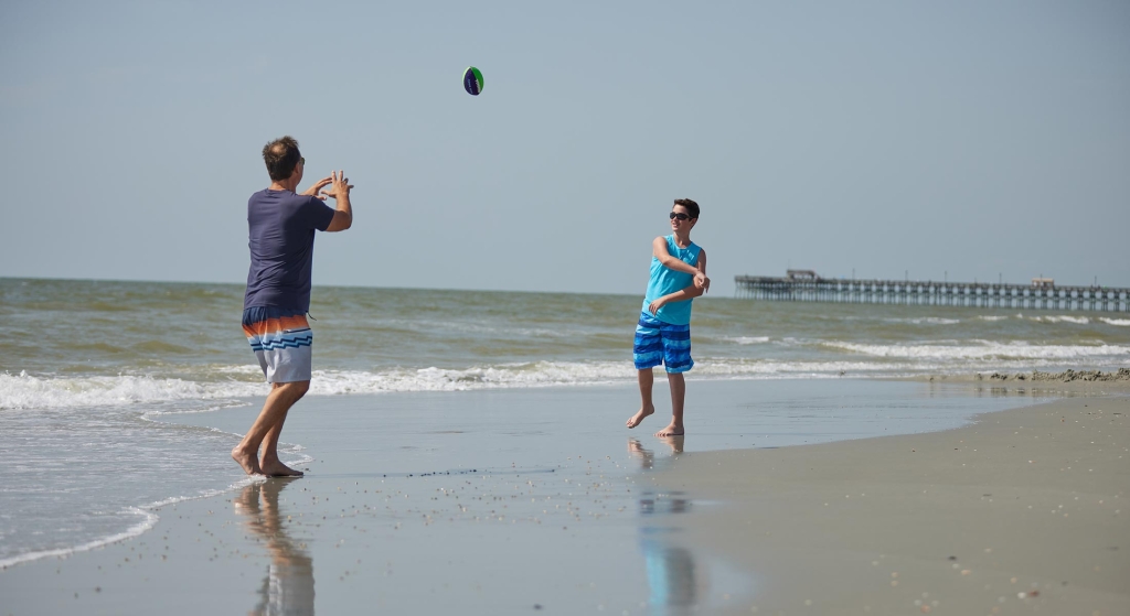 Father and son throwing football on beach