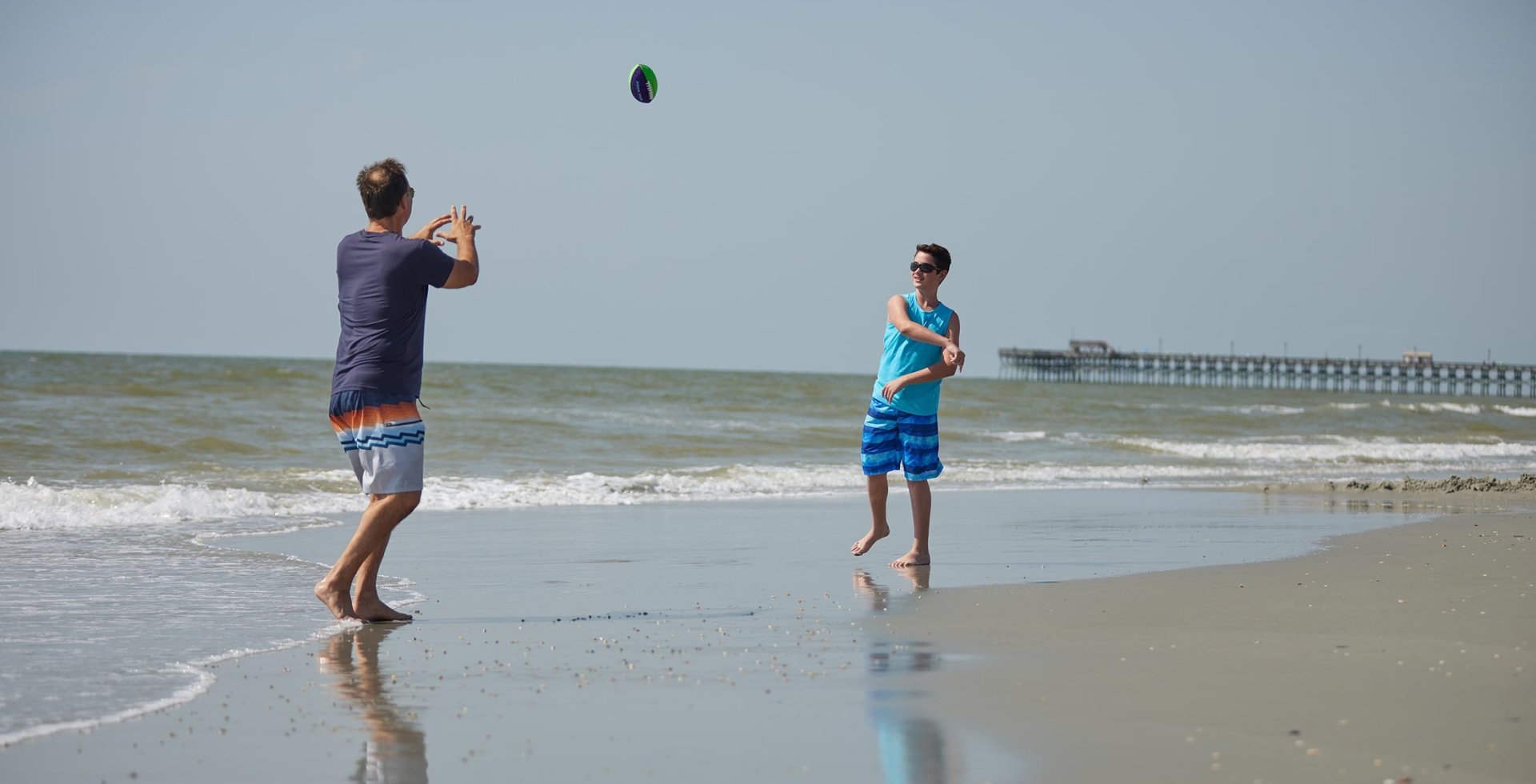 Father and son throwing football on beach