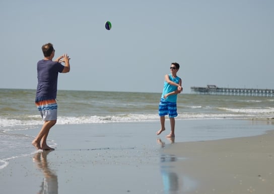 Father and son throwing football on beach