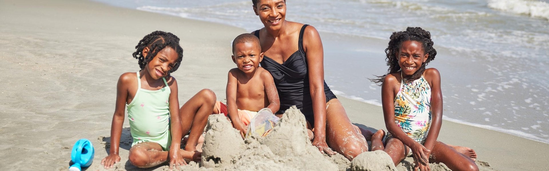 Mom building sandcastles with her 3 children