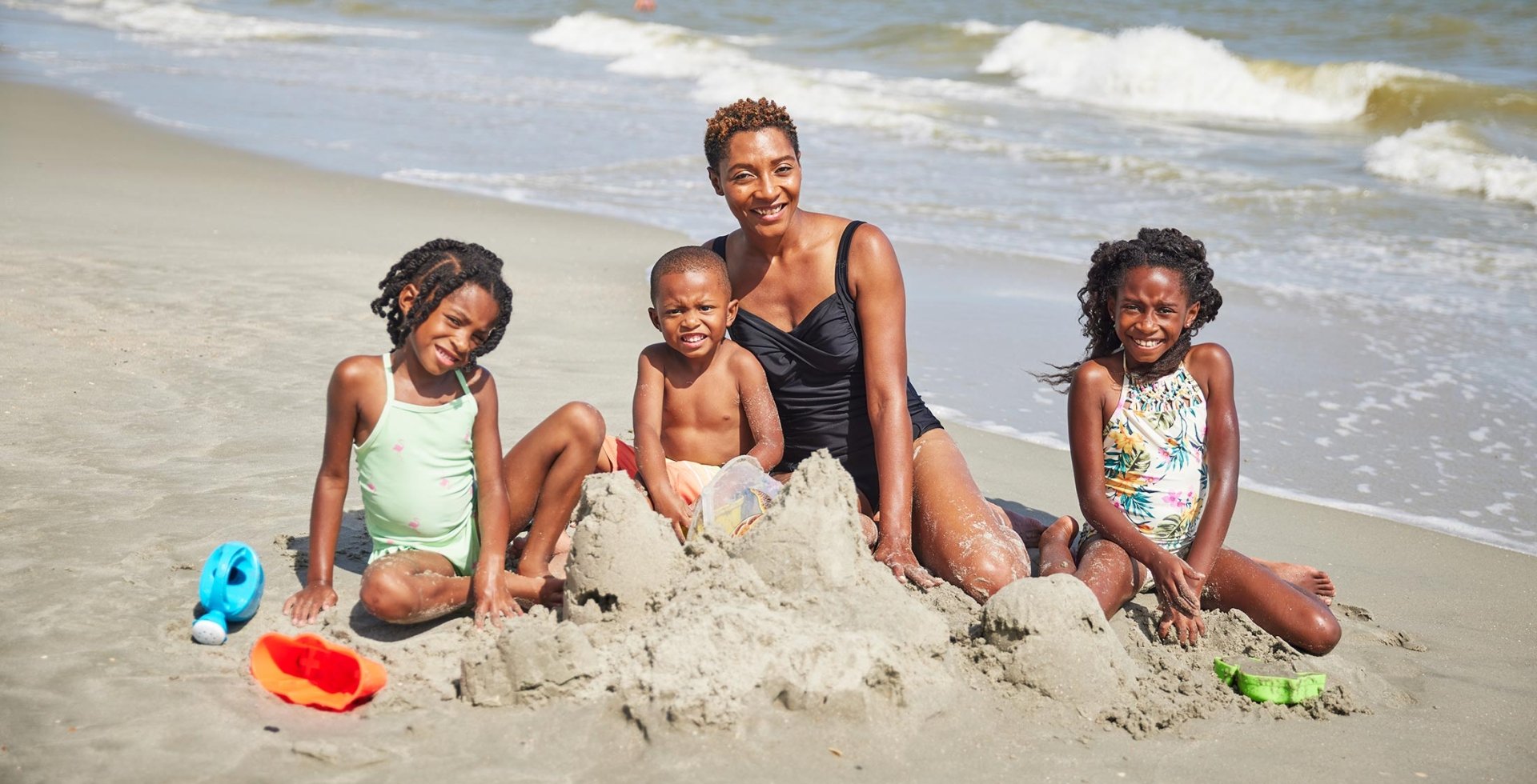 Mom building sandcastles with her 3 children