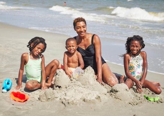 Mom building sandcastles with her 3 children
