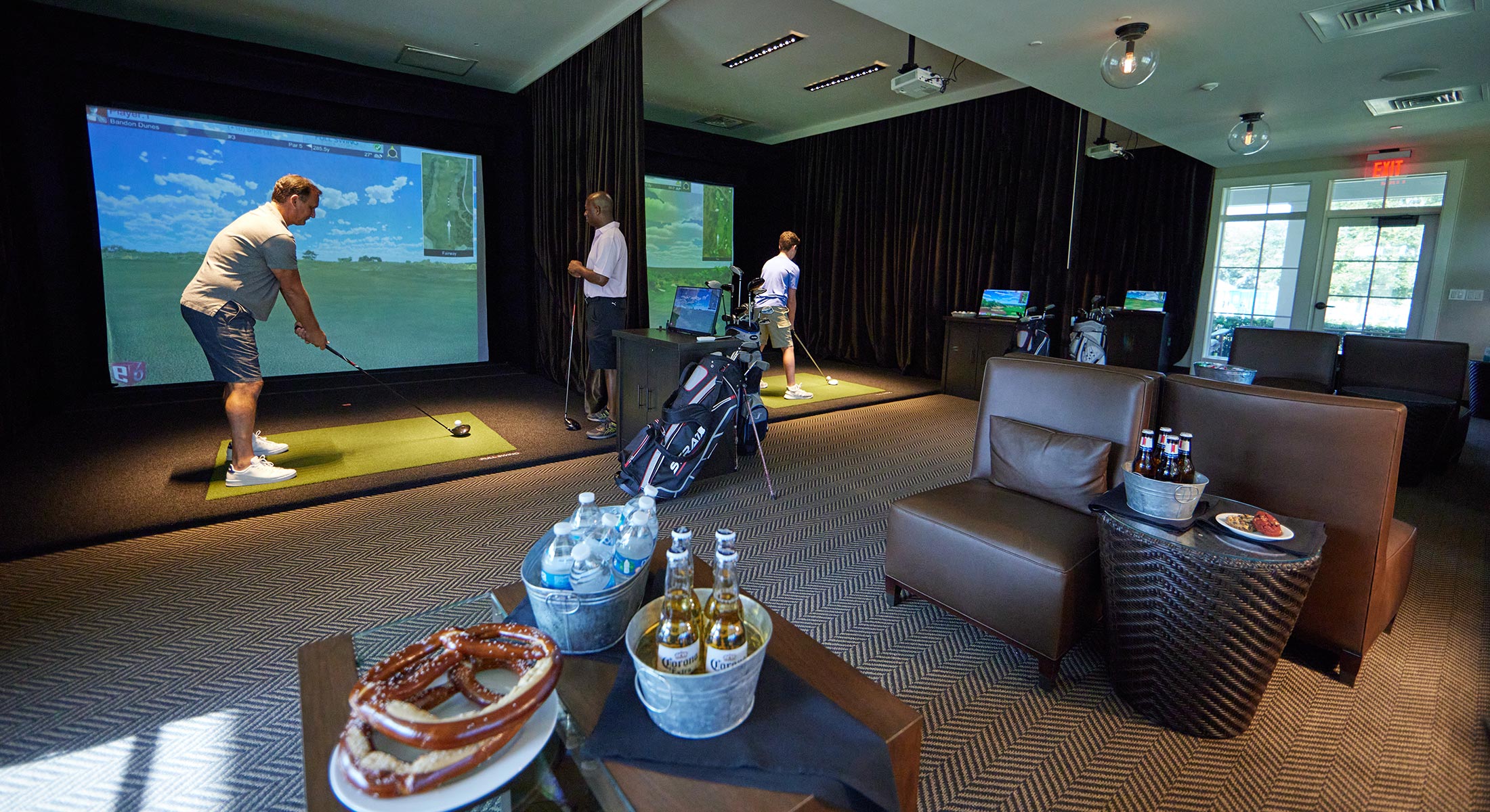 Men playing the Golf simulators at The Landing with buckets of beer, and water, and snacks such as pretzels and cookies