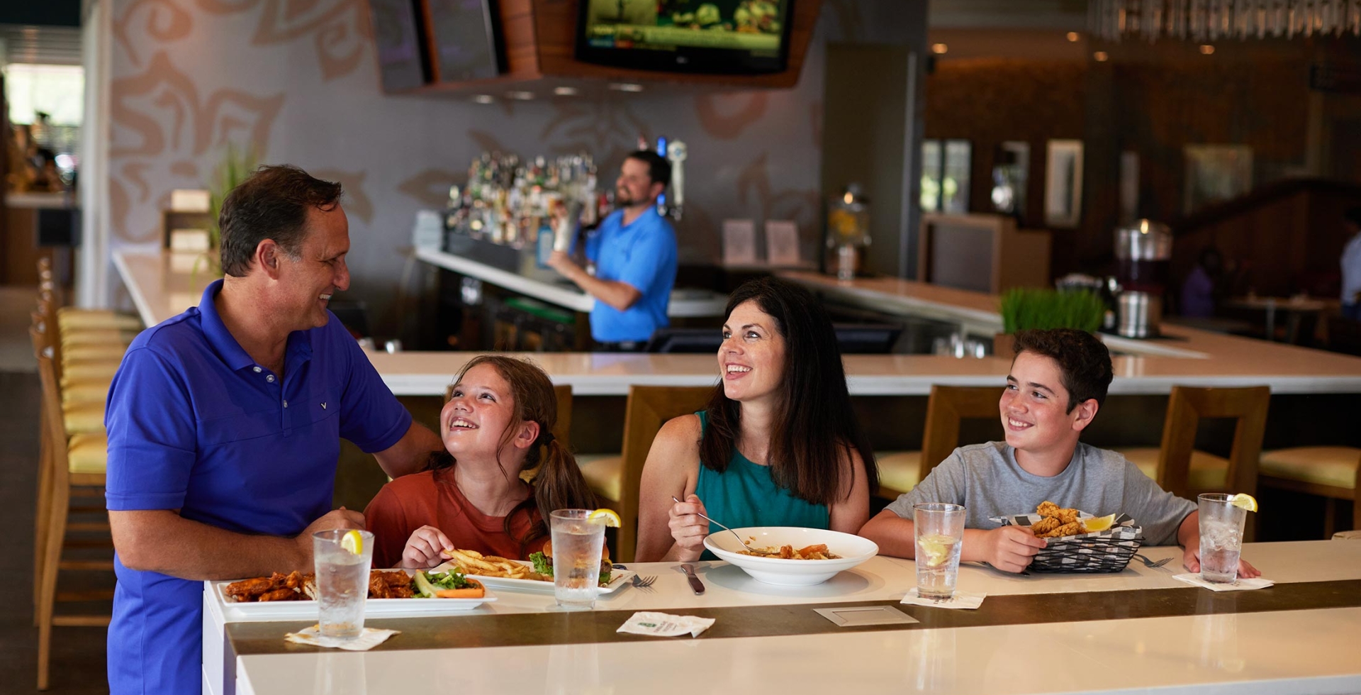 Family enjoying their meal at Coastal Grill at one of the high-top tables