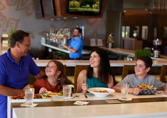 Family enjoying their meal at Coastal Grill at one of the high-top tables