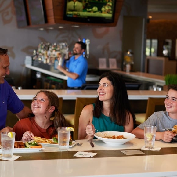 Family enjoying their meal at Coastal Grill at one of the high-top tables