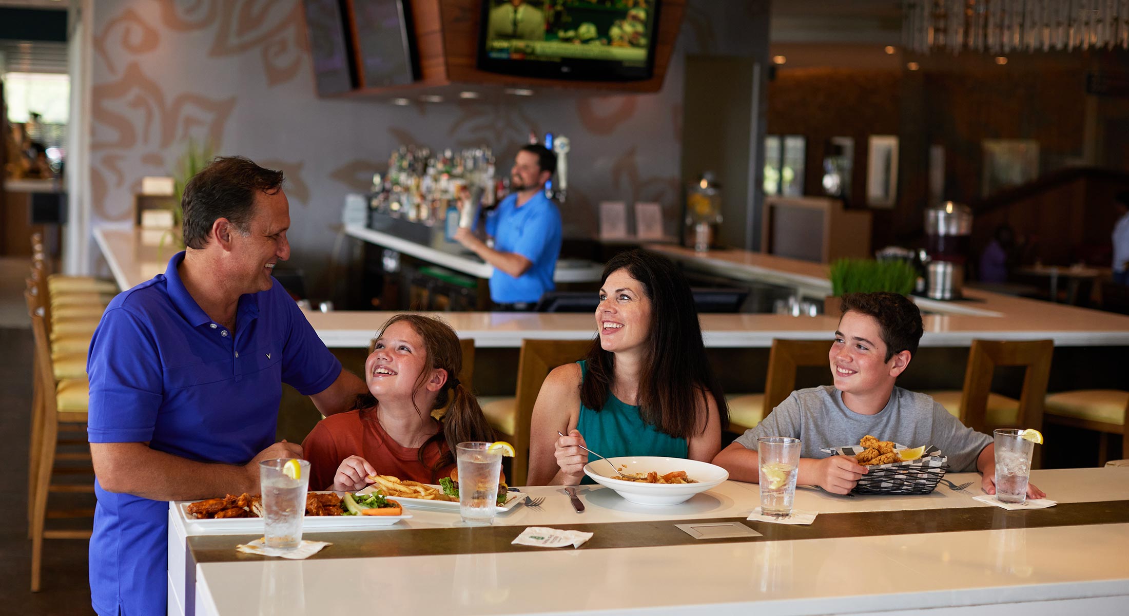 Family enjoying their meal at Coastal Grill at one of the high-top tables