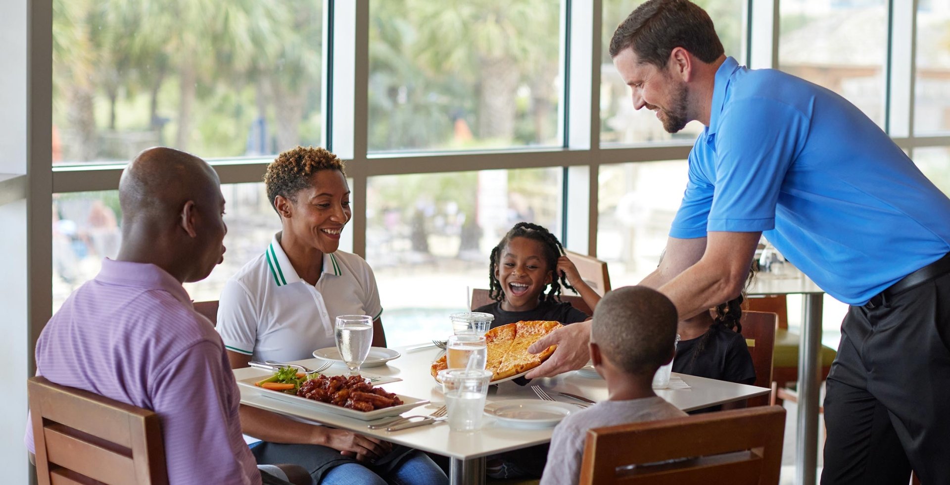 Family being served pizza at Coastal Grill