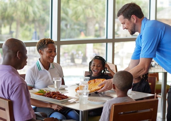 Family being served pizza at Coastal Grill