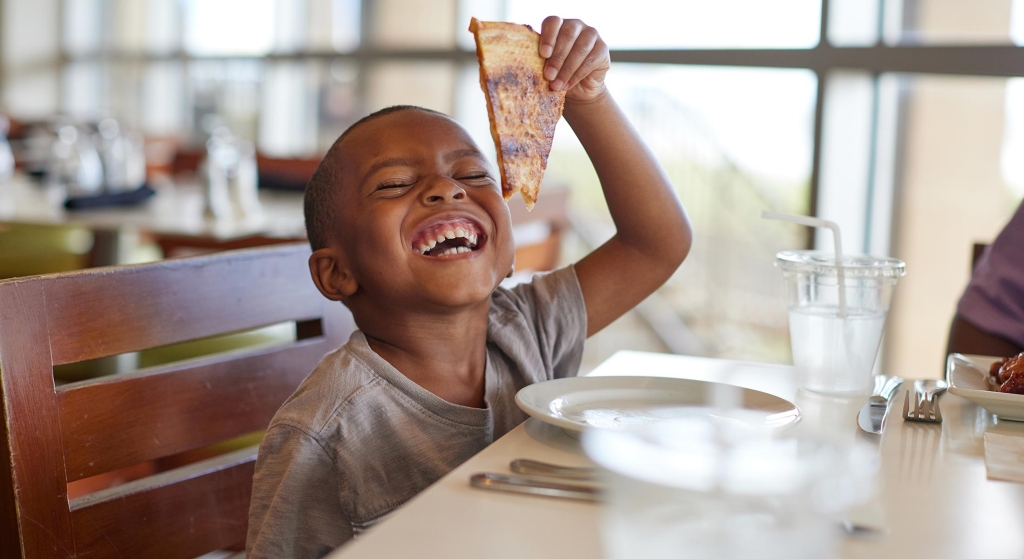 Kid holding slice of pizza