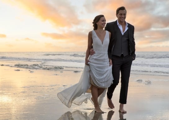 Bride and groom walking on the beach