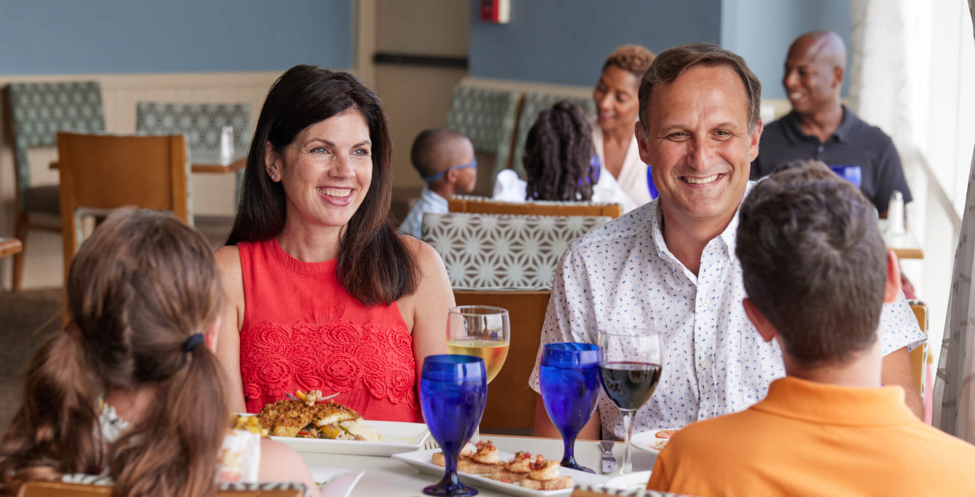 Family sitting at restaurant table and smiling