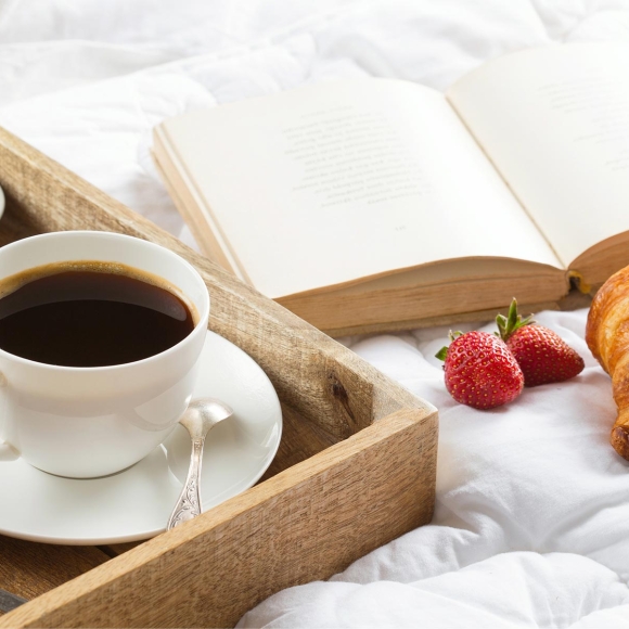 Breakfast in bed with a book. Coffee, croissants with jam and butter, and fresh strawberries