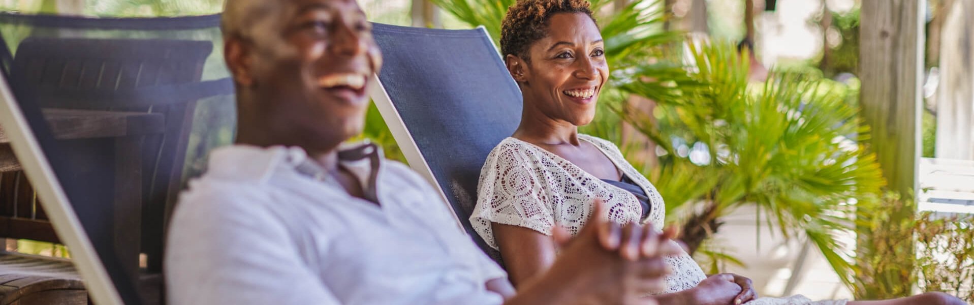 A couple lounging and laughing in the Cabana lounge chairs on our Hilton pool deck
