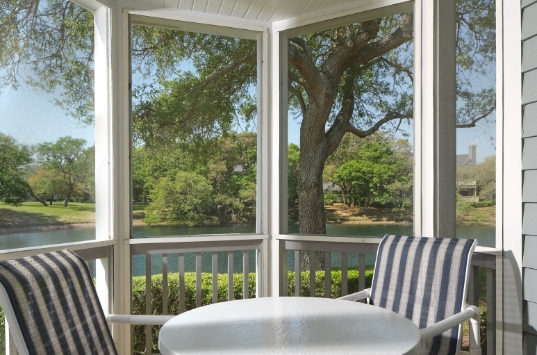Windermere by the sea screened in porch with a table and chairs and a pond view