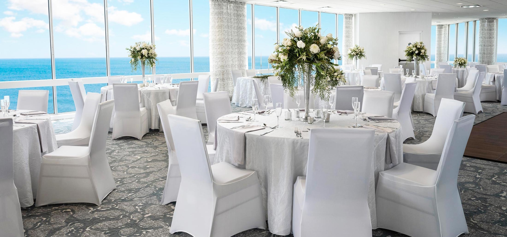 Tables set for wedding in ocean view ballroom