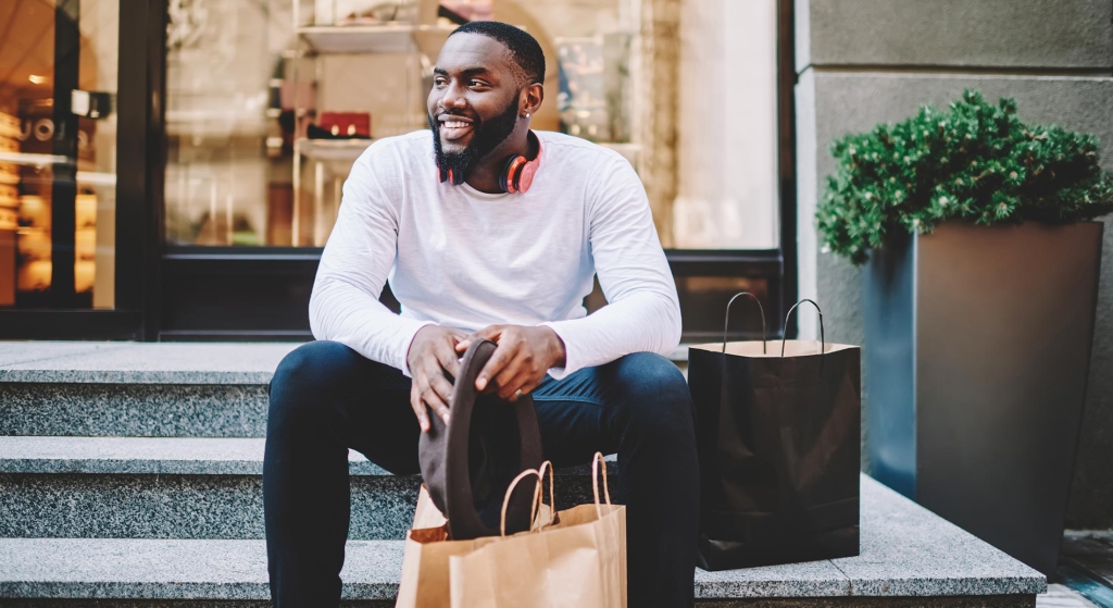 Man sitting on stairs with shopping bags.