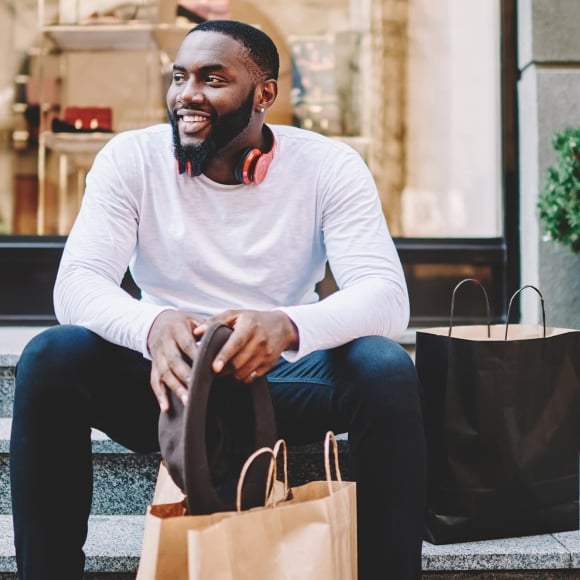 Man sitting on stairs with shopping bags.