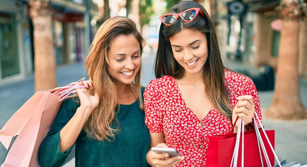 Two women shopping and looking at phone