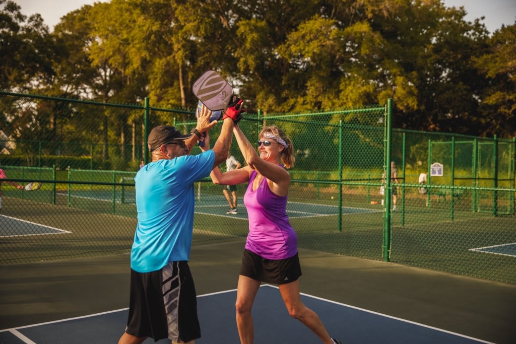 Two people high five on a pickleball court