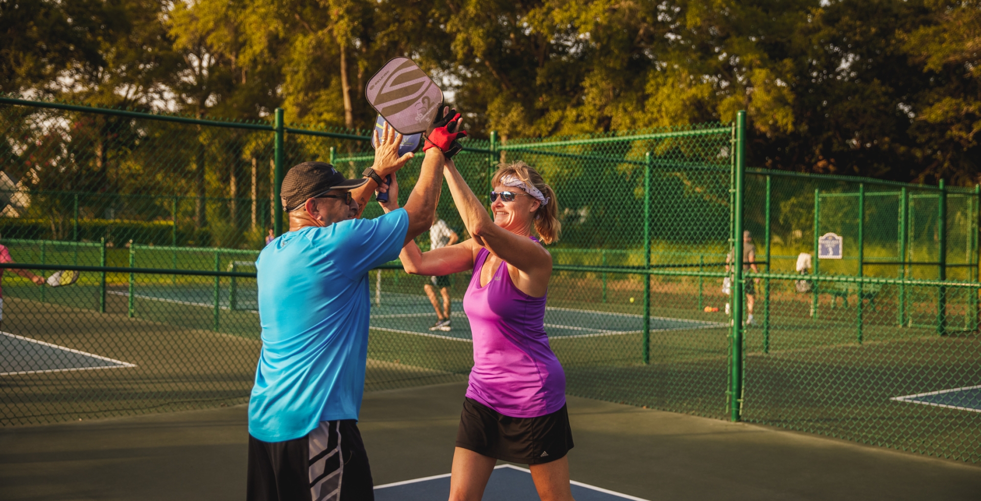 Two people high five on a pickleball court