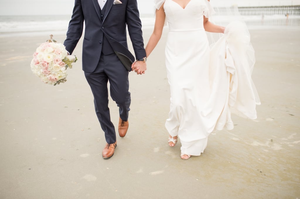 Wedding couple holding hands on the beach.