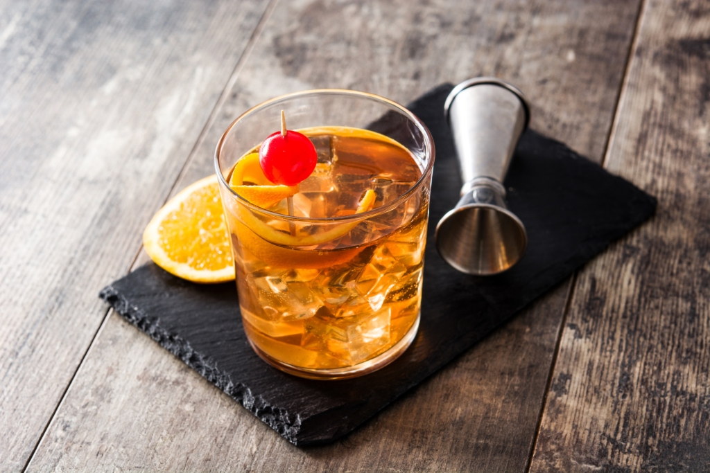 Old fashioned cocktail with orange and cherry on wooden table