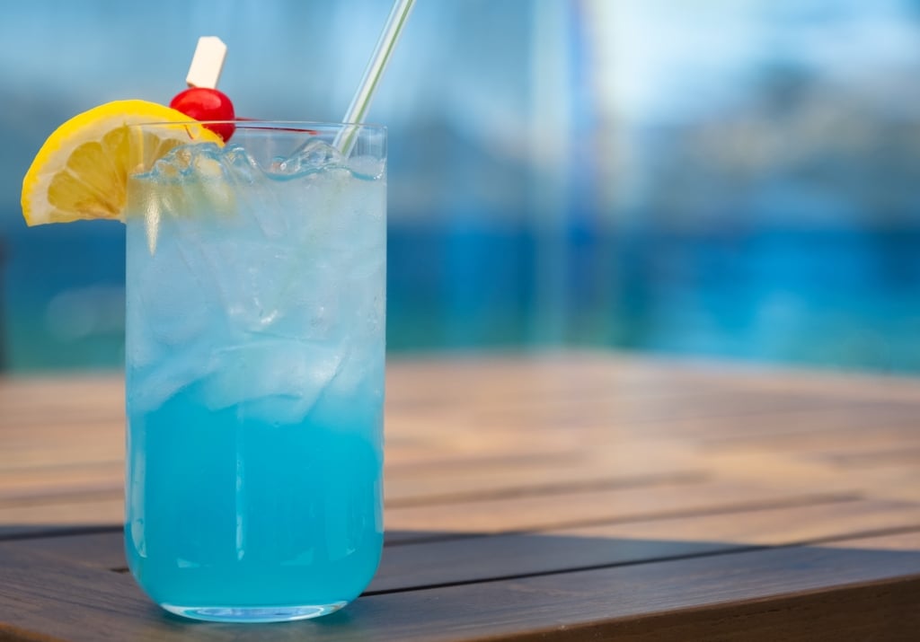 Blue cocktail with a lemon wedge and cherry garnish