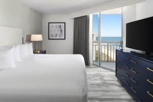 Hotel room with king size bed, blue dresser and ocean view balcony