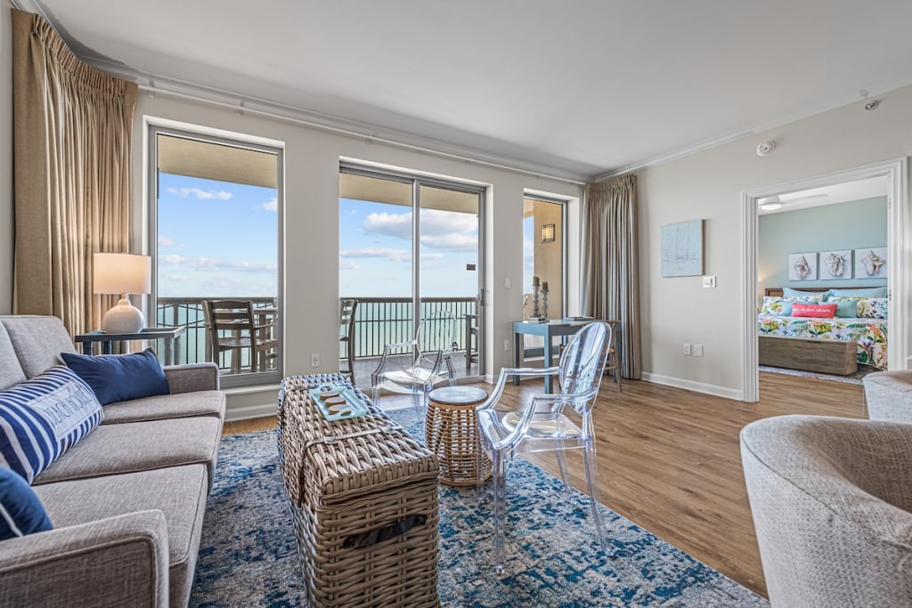 Condo living room with sofa, plastic chair and wicker coffee table with a oceanfront balcony