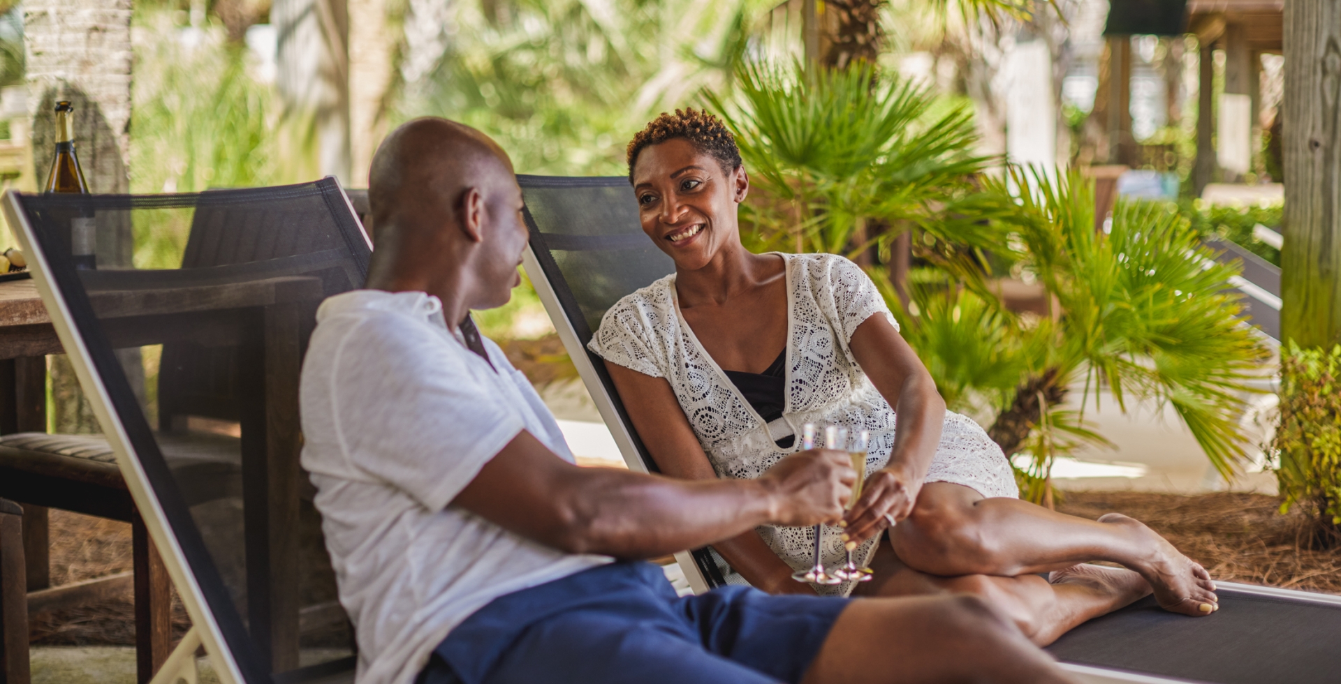 A couple cheers champagne glasses in a Hilton poolside cabana