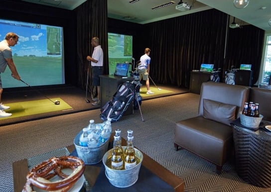 Men using the three Golf Simulators at The Landing with buckets of beer and water, pretzels, and chicken wings.
