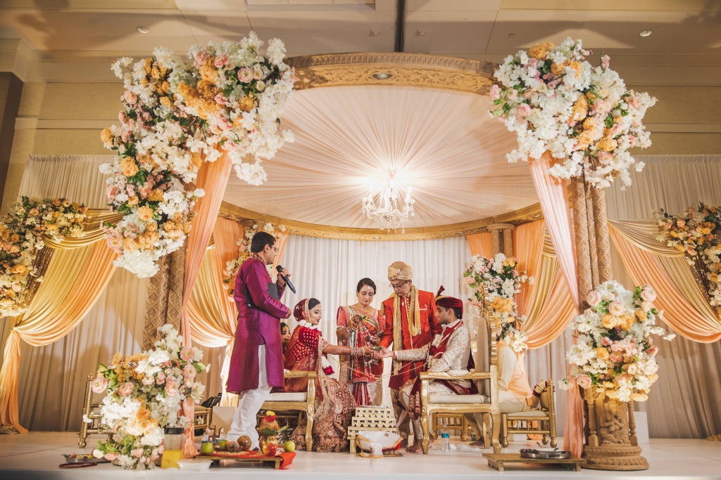 A couple sits in a wedding chapel decorated with exquisite peach florals.