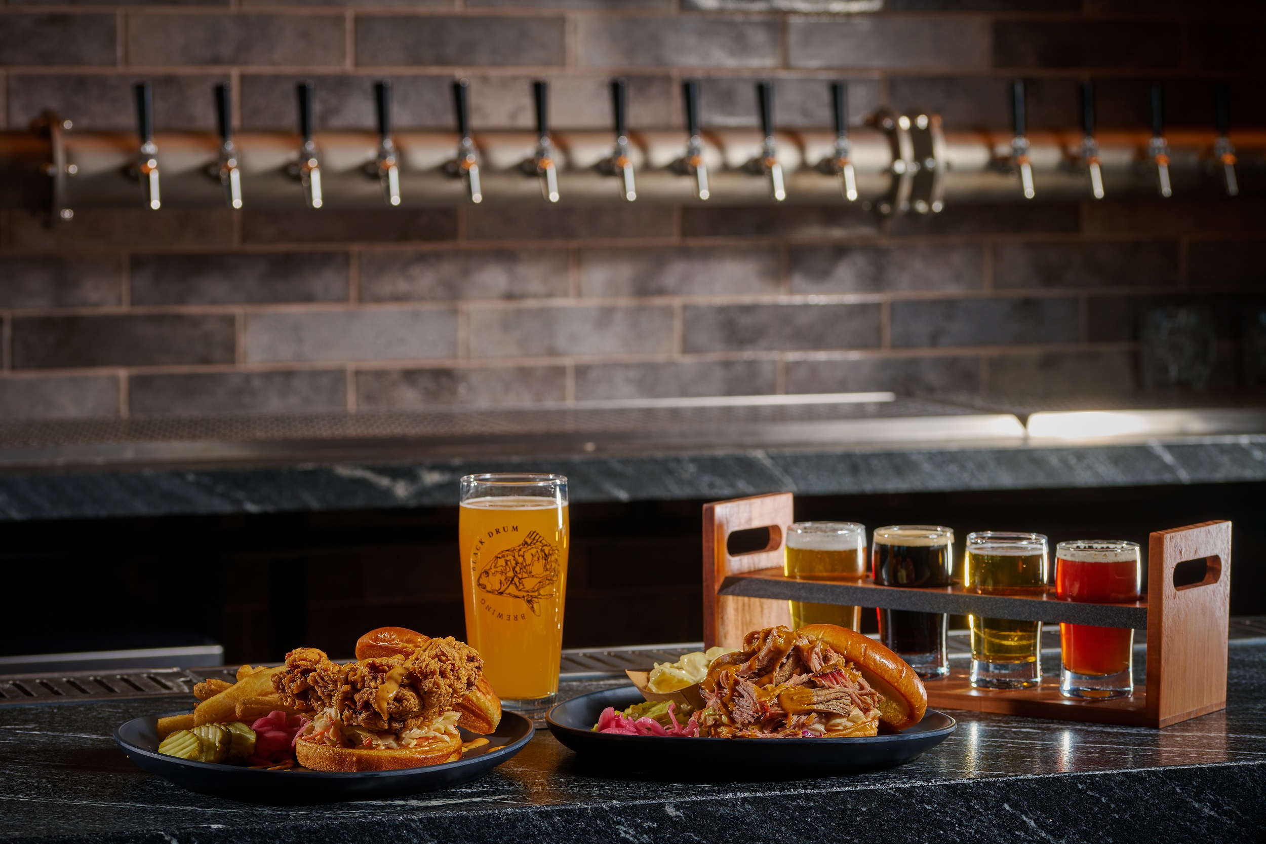 Black Drum Brewing Fried Chicken sandwich and pulled chicken sandwich with a pint of beer and a beer flight