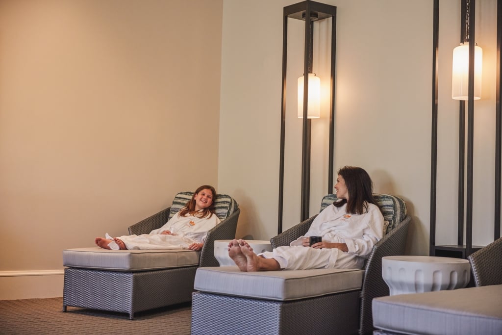 A mother daughter sit at a spa in robes.