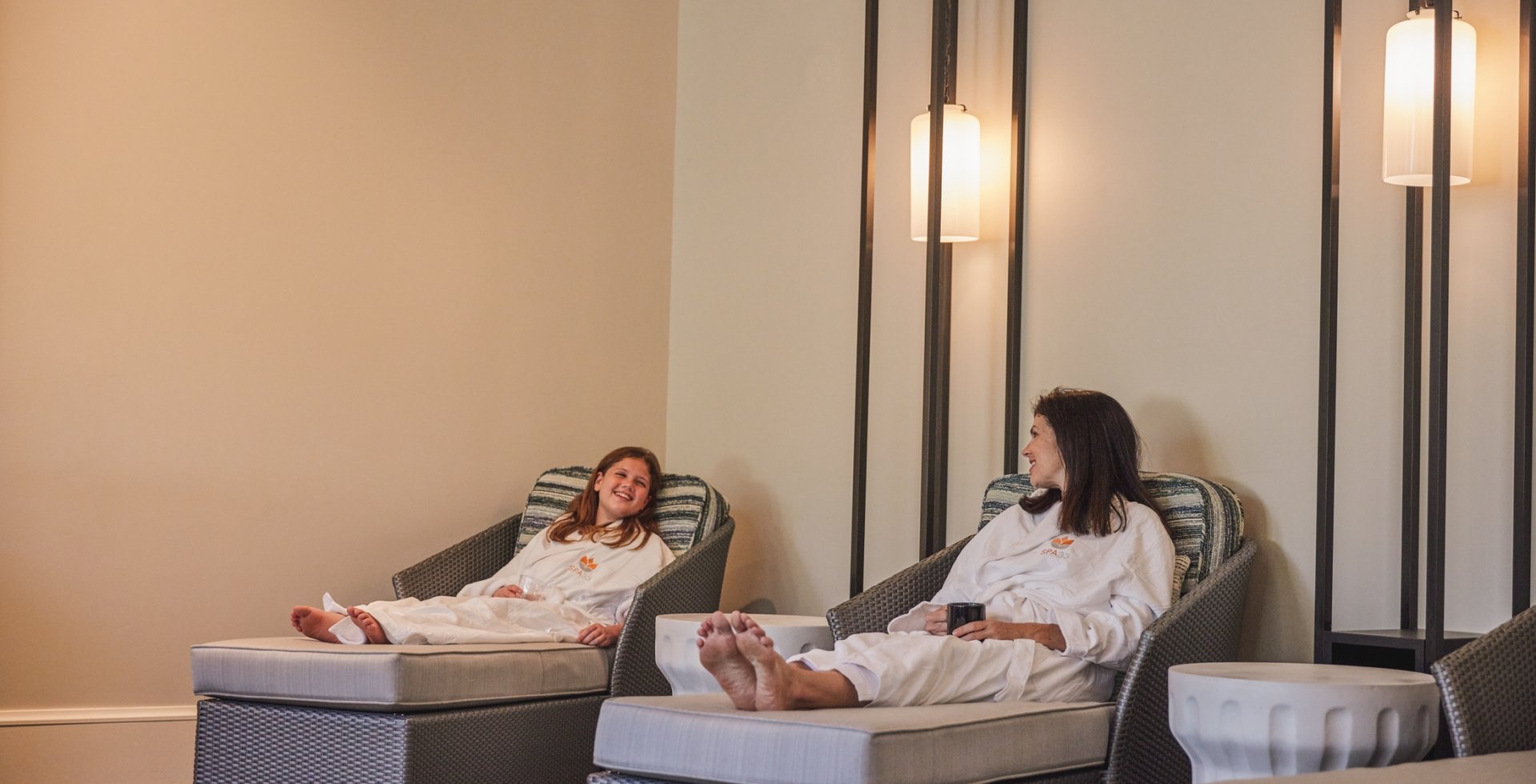A mother daughter sit at a spa in robes.