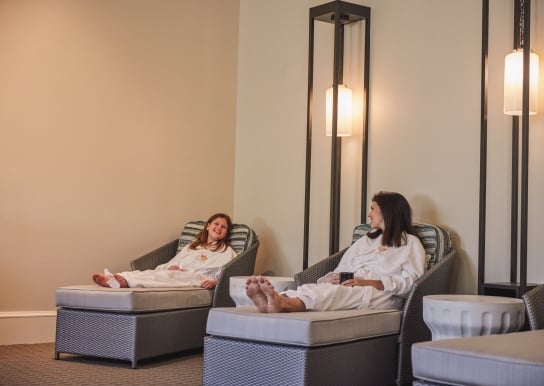 A mother daughter sit at a spa in robes.