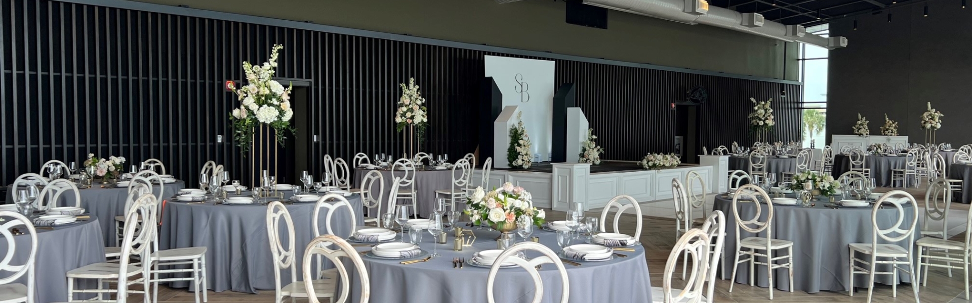 Seaside Vista set up for a wedding reception. Round tables for dinner service, a dance floor and a stage.