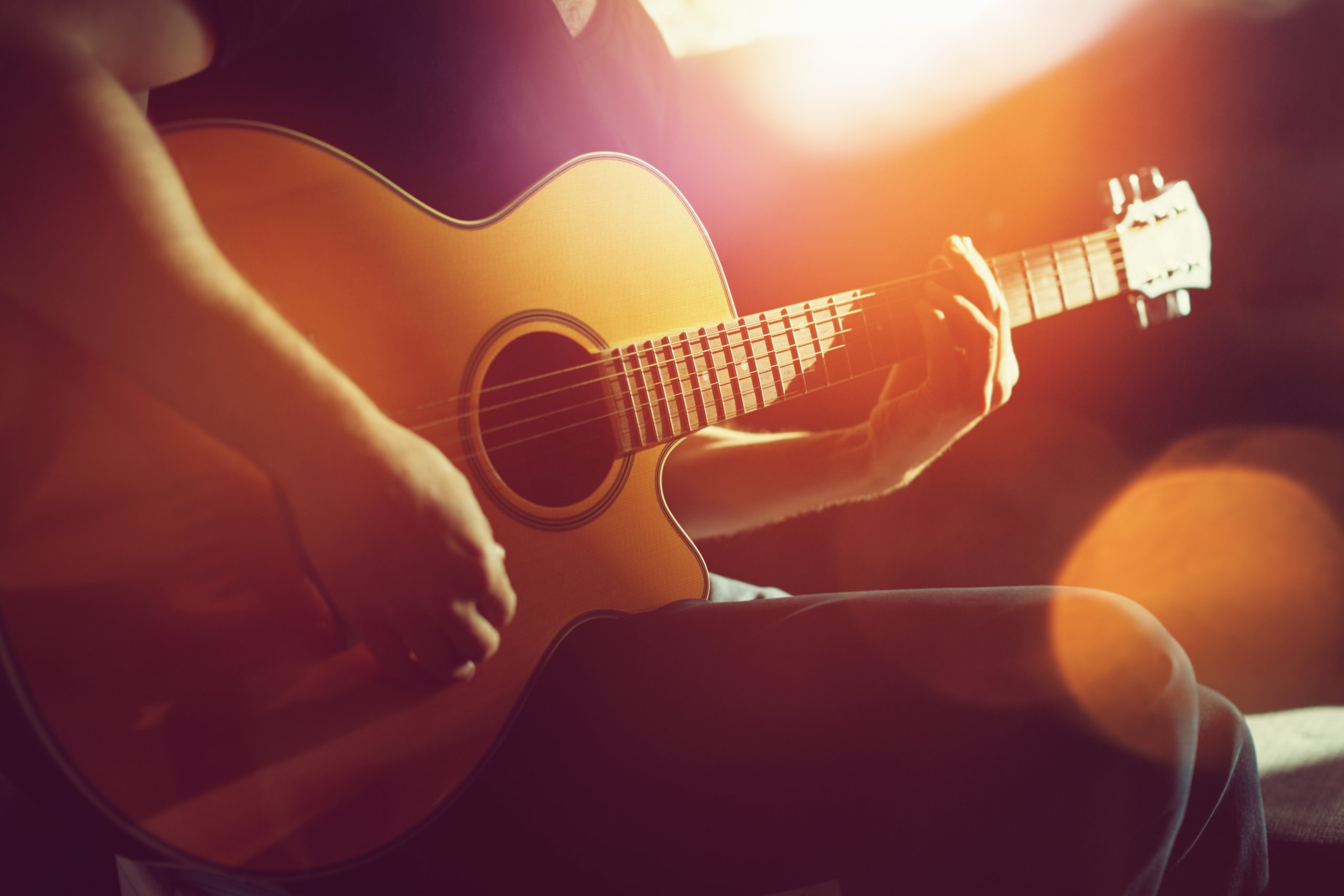 Close up of guy playing the acoustic guitar