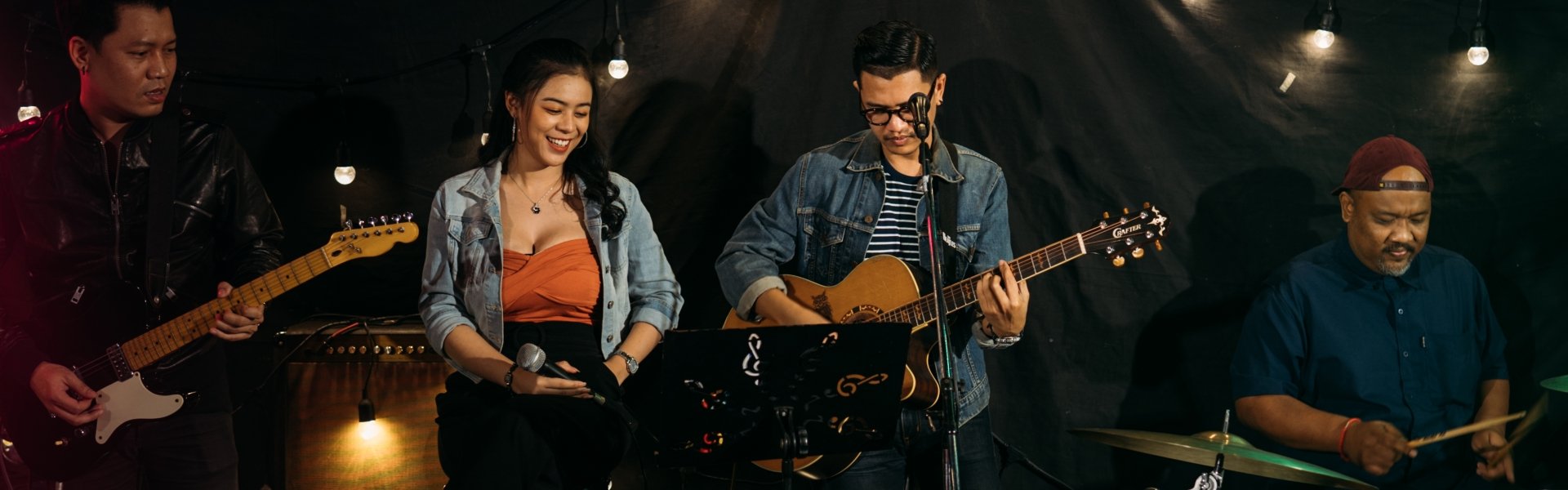a band playing guitars, and drums and a girl with a microphone in her hand