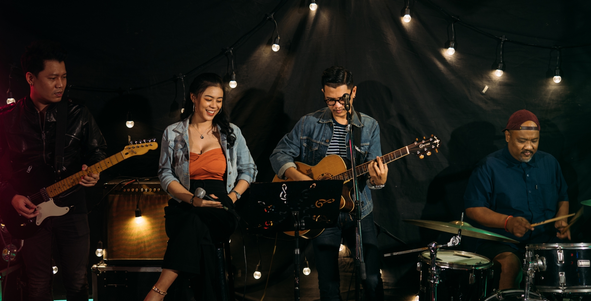a band playing guitars, and drums and a girl with a microphone in her hand