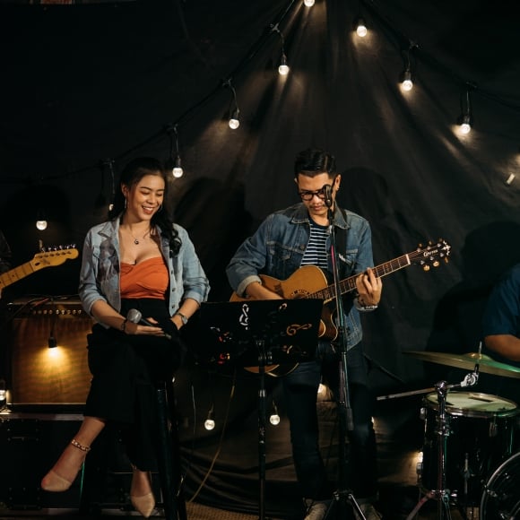 a band playing guitars, and drums and a girl with a microphone in her hand